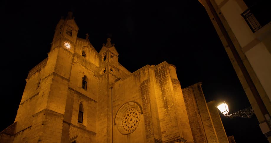 A tall church at night in Spain has a clock tower