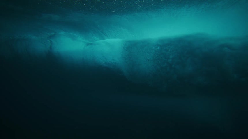 A wave crashes under the surface of the ocean