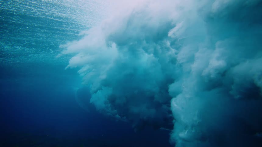 Underwater view of the ocean with foam from the impact of a breaking wave
