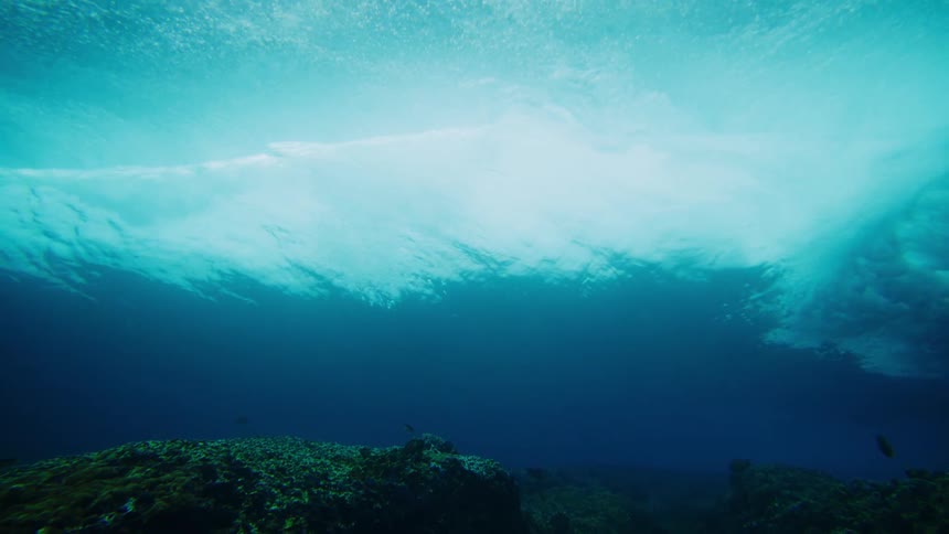 Underwater view of coral reefs in the ocean and a strong wave passing by