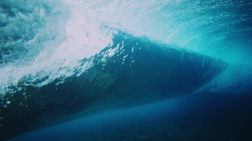 Inside view of crystal clear blue ocean and a crashing tubular wave