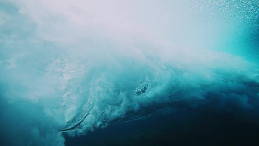 Underwater view of clear ocean waters with a strong tubular wave passing by