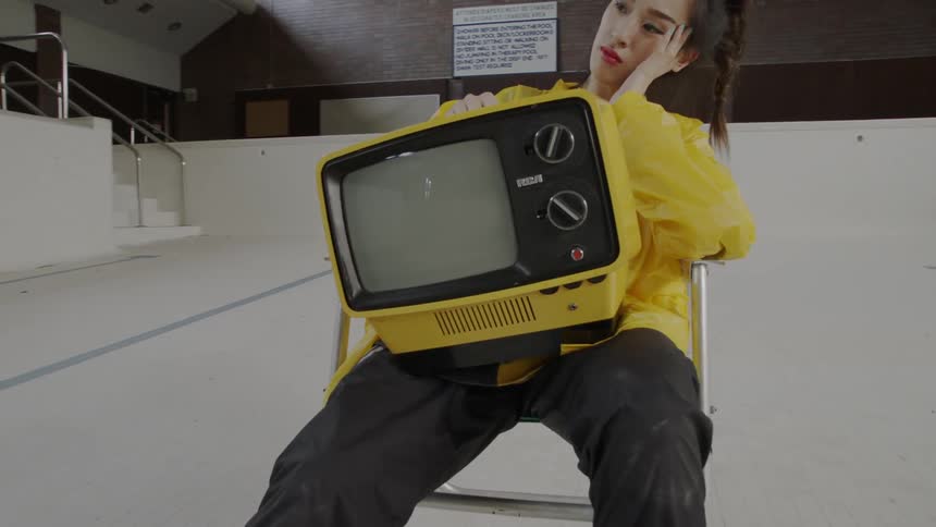 Woman sitting on a chair looking bored with a tv on her lap