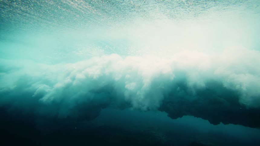 Interior view of turquoise blue water and a wave with foam breaking