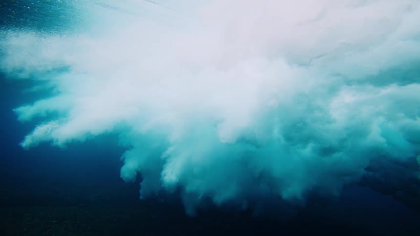 A large cloud spreads underwater as the wave crashes