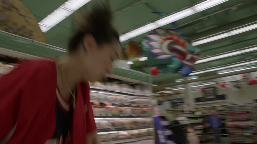 A young woman is dancing in the cold section of a grocery store