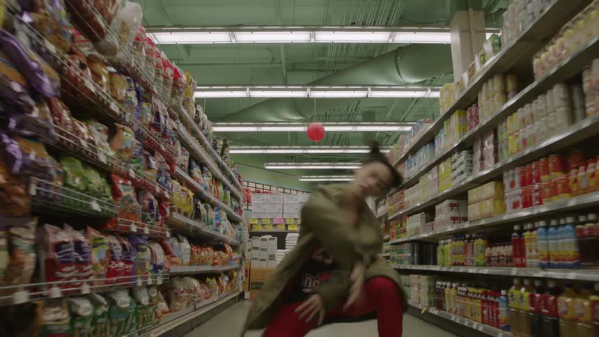 Woman dances interpretively in the aisle of a grocery store