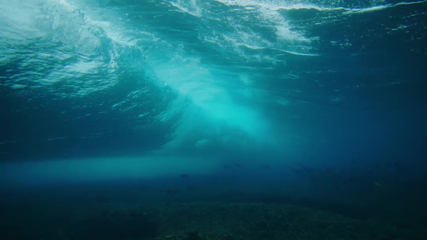 Underwater view from ocean floor of wave crashing above