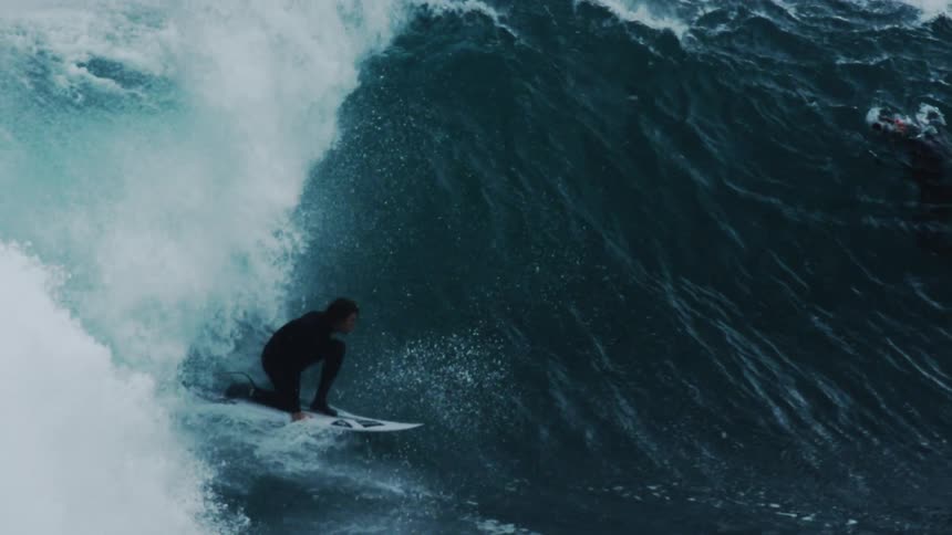 People watching a surfer riding a strong tubular wave in the ocean