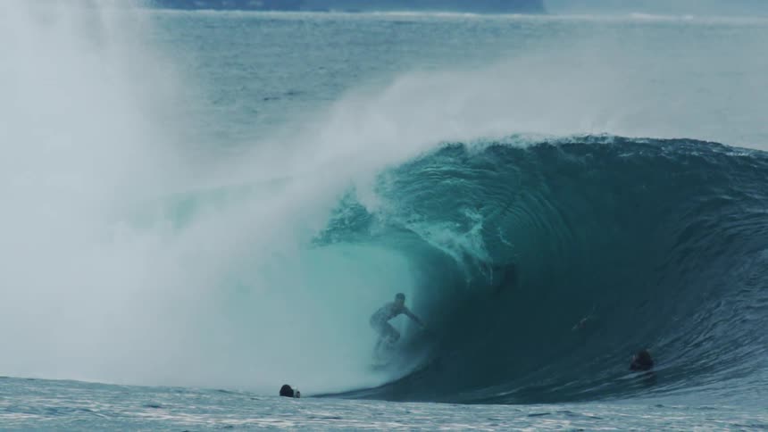 Surfers in the ocean with one of them riding a tubular wave
