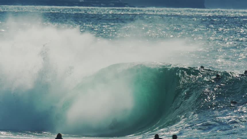 People in the ocean with one of them surfing a tube wave