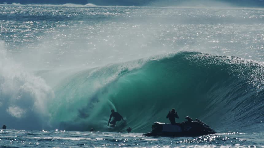 The man surfing a wave is being filmed