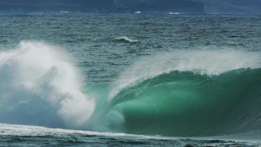 A large wave is crashing by the shore