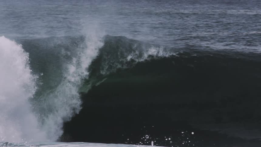 A large wave slowly falls in the vast ocean
