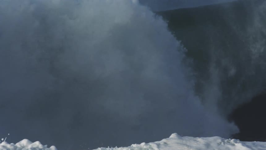 Large wave swells then breaks filling the air with spray and creating foam