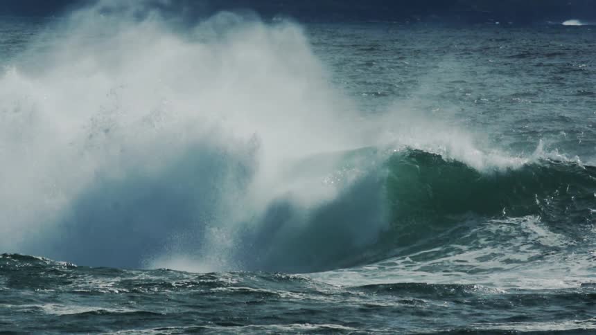 A wave crashing in on itself when it crashes it sets off a wide spread array of mist and white foam appears when it is all complete
