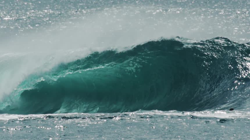 A small group of surfers are paddling on an ocean wave while another person sits on a jet ski