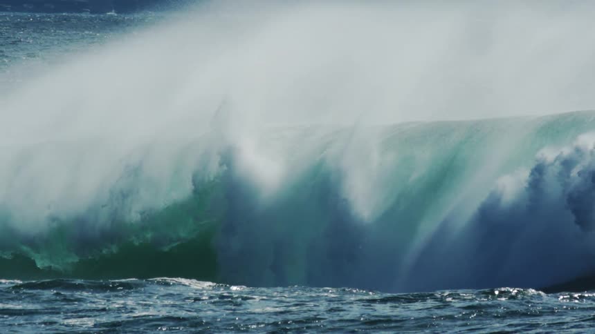 Surfers in the ocean with a big tubular wave breaking
