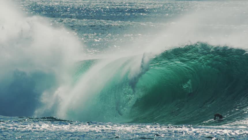 Photographers film a powerful wave while swimming in the ocean on a sunny day