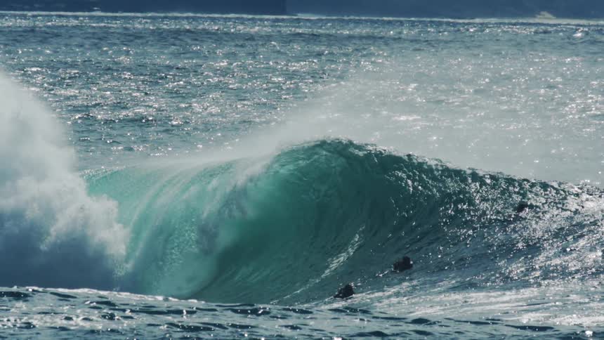 Surfer falling into a tubular wave and other people watching and filming