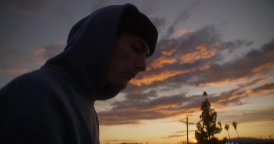 A man is walking on the field at sunset
