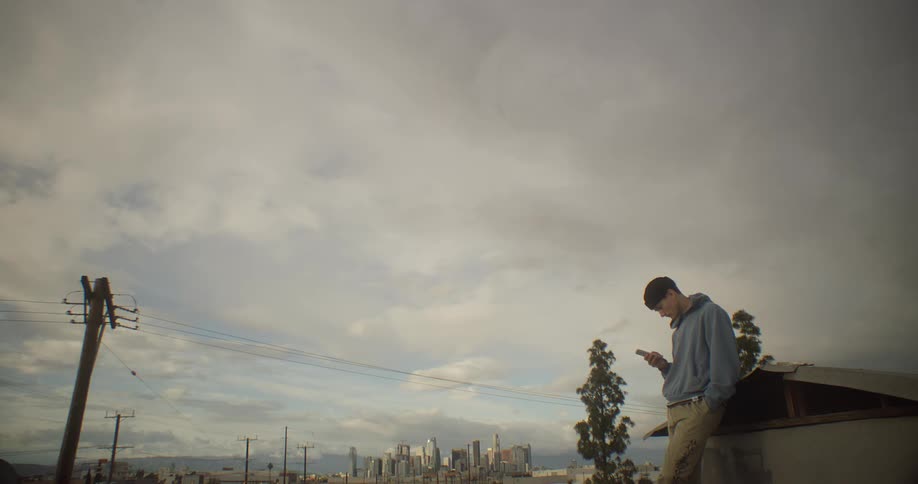 A man is leaning and texting on his cell phone