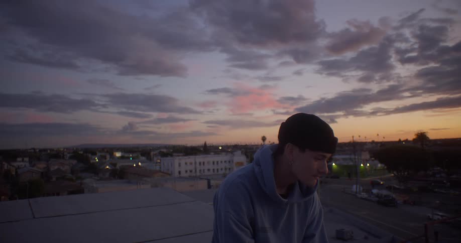 Man sitting on an outdoor terrace in the late afternoon overlooking a cityscape