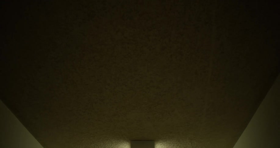 Illuminated spackled ceiling around a florescent light fixture in a dark hallway corridor