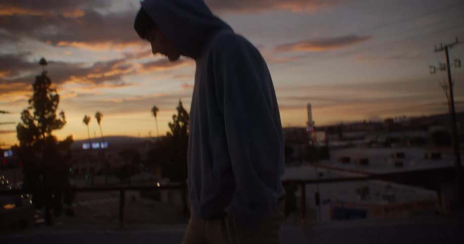 Man in a cap walking along a terrace in the late afternoon