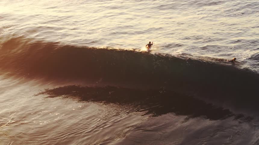 Aerial view of two surfers riding a wave in the ocean
