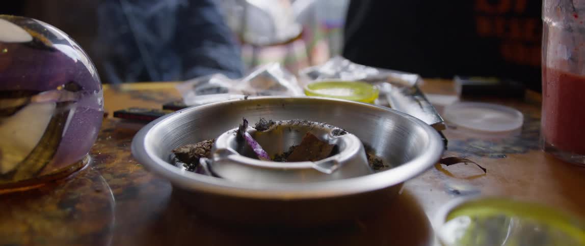 Close up of a table with an ashtray and a glass of juice in the background and other instruments