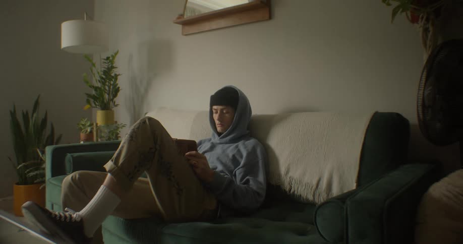 A teenager is using his tablet on the couch