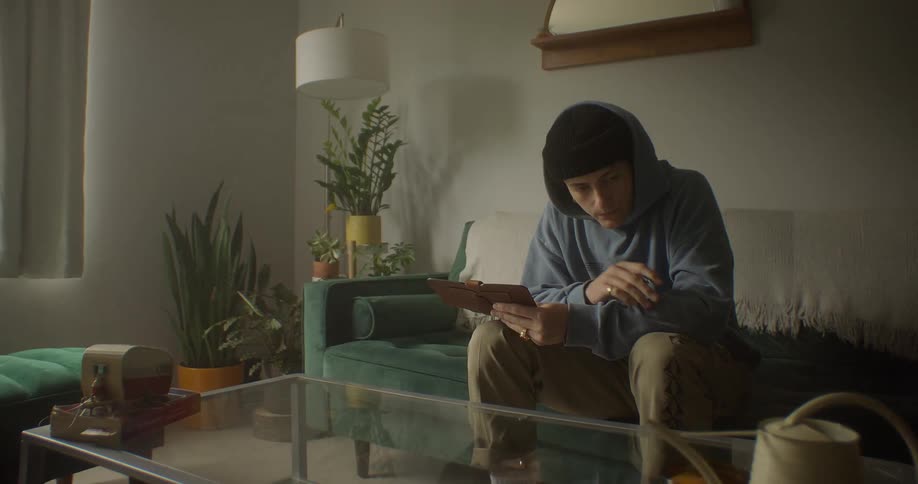 Concentrated and thoughtful man sitting in living room writing on a notepad