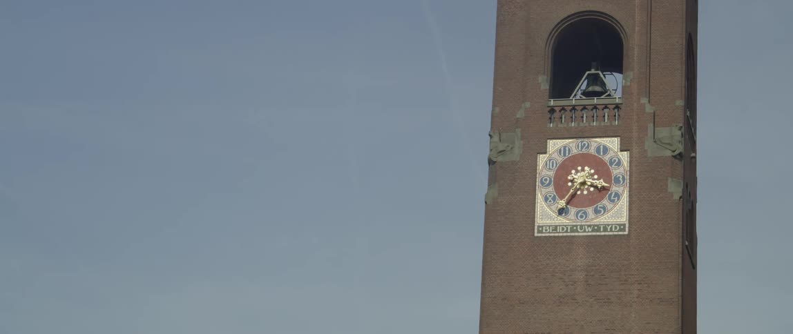 The clock tower of the beurs van berlage in amsterdam under a clear light blue sky