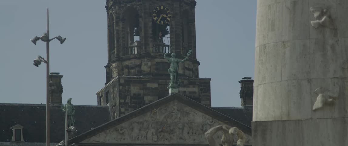 A bell tower has a statue in front