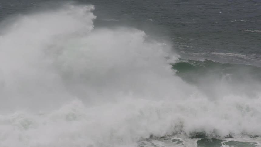 Large wave breaks filling the air with water sprayduring the day