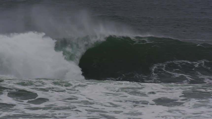 Under a dark overcast sky powerful dark waves crash and churn creating a turbulent sea with white foam and spray