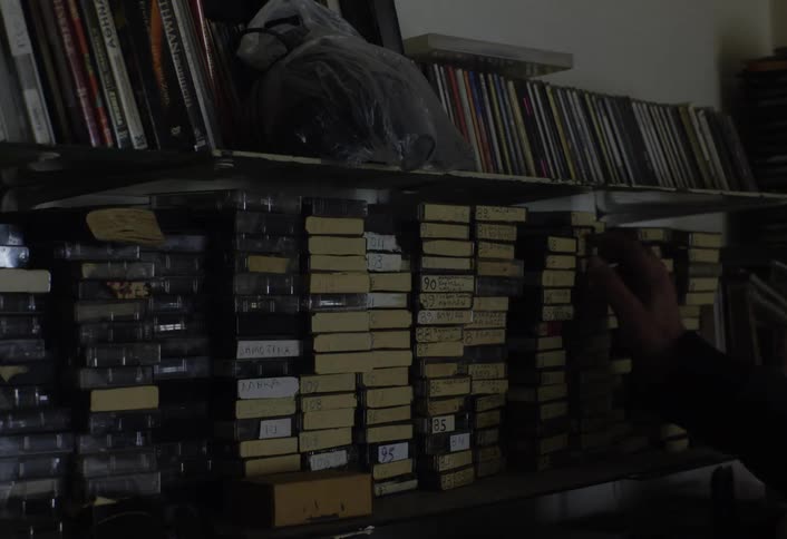 A person removes a tape from the shelf