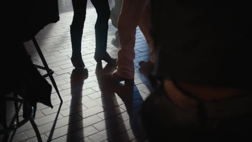 People in a bar are dancing near people sitting on stools