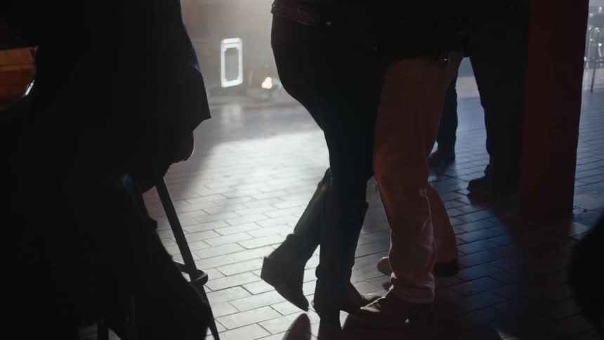Couple dances in the narrow space available in a bar during the daytime