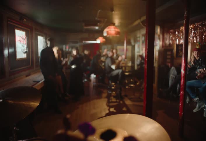 People inside a bar clapping and looking in the same direction at a musical group