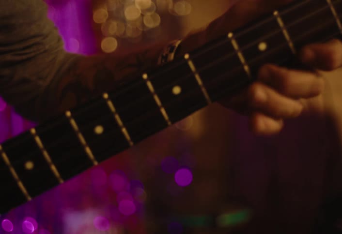 An old man is standing and playing guitar