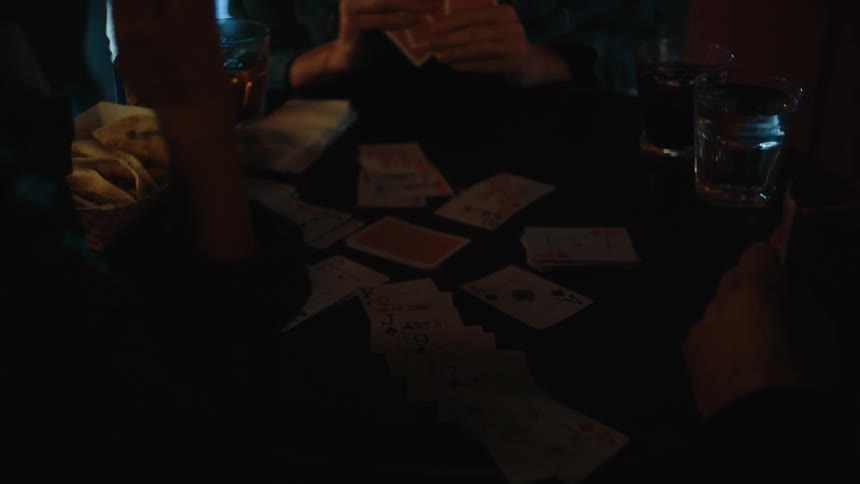 People sitting at a bar table playing cards