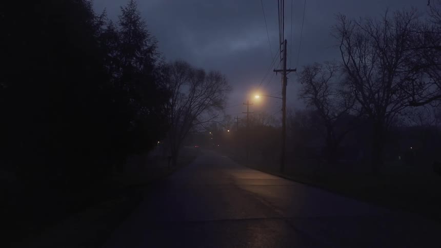 Fog shrouds street lights and a rural area at night