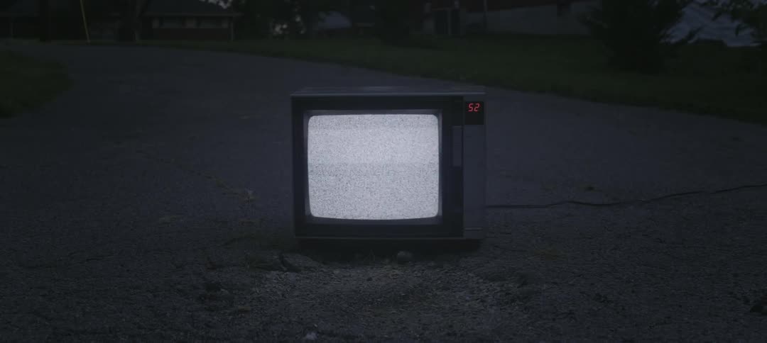 A small tv is sitting on a street playing only white noise