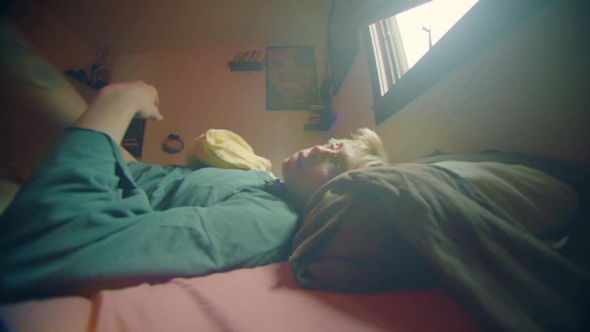 Woman rolls over in bed and throws off her blanket