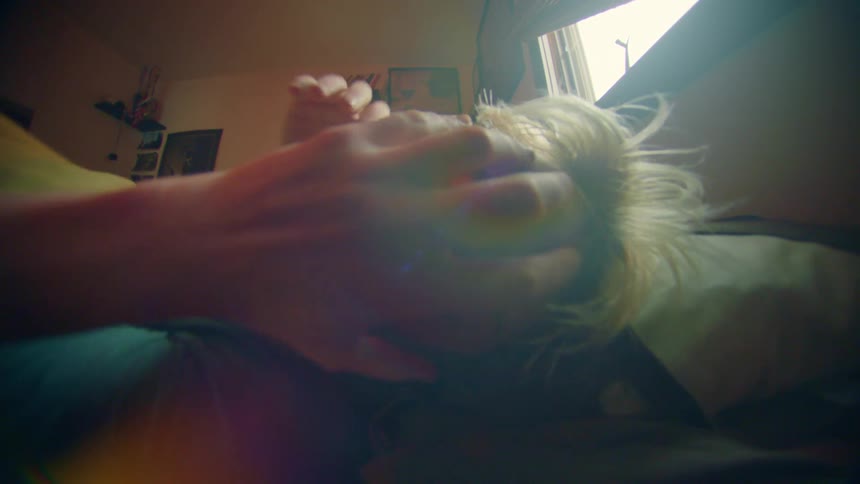 A woman looks upset as she rolls over in bed then gets up