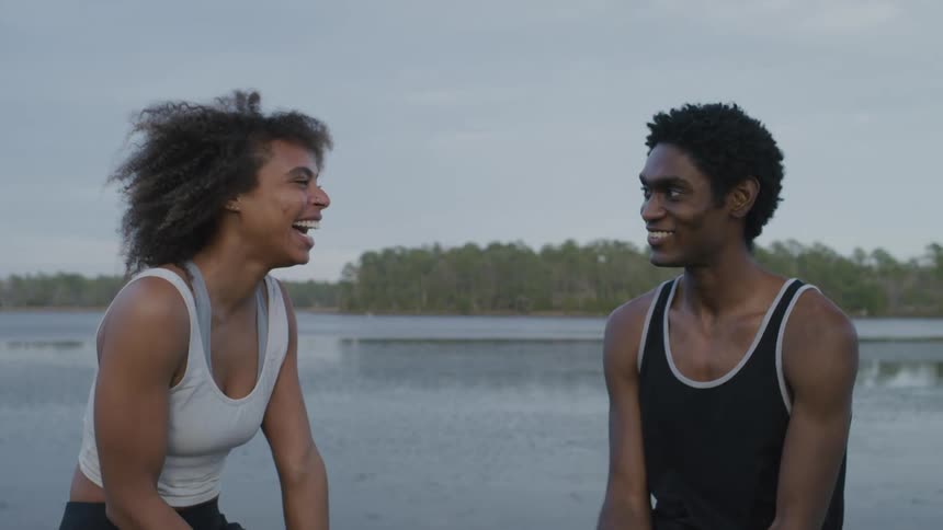 A woman laughs as a man talks by the lake