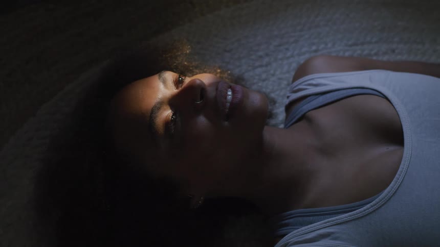 A woman is smiling as she lays on a braided rug on the floor