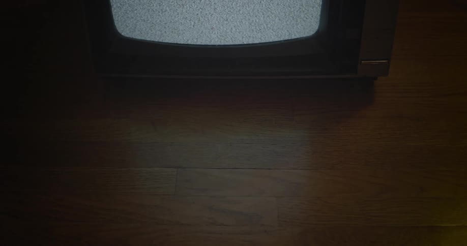 Partial view of a tv flickering static on a hardwood floor